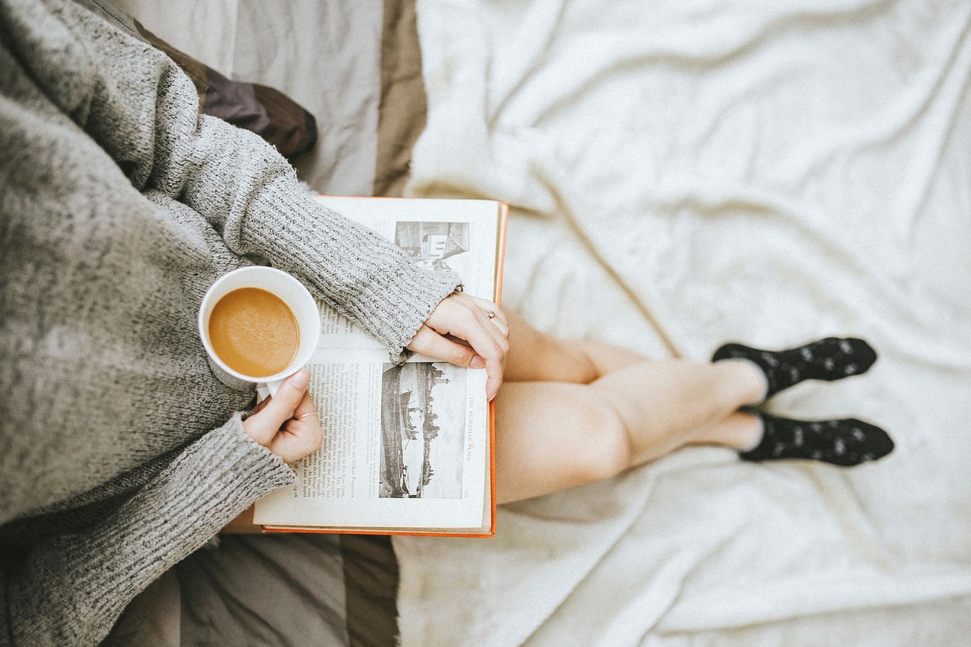 Person resting in bed with a warm drink and a book, decompressing after a holiday event during eating disorder recovery