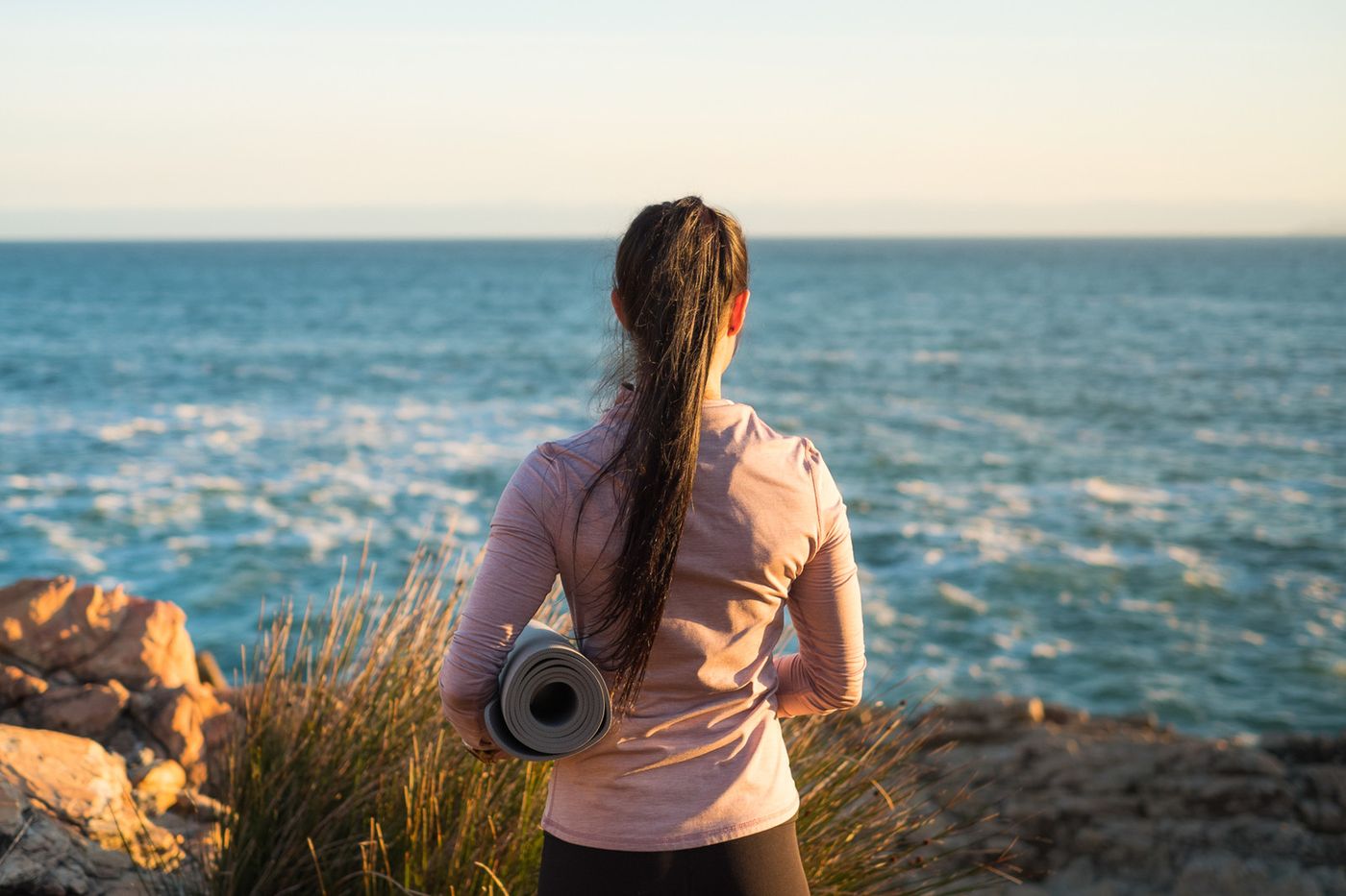 Woman sitting quietly by the ocean, a calming mindfulness practice for coping with grief, supported by grief counseling in Berkeley